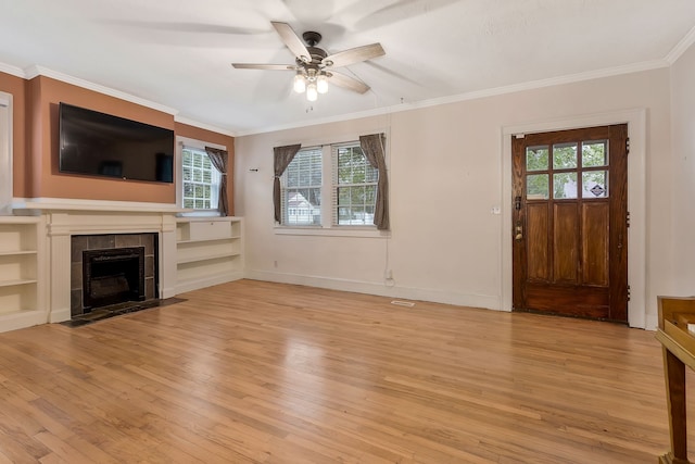 unfurnished living room featuring plenty of natural light, ceiling fan, a tile fireplace, and light hardwood / wood-style flooring