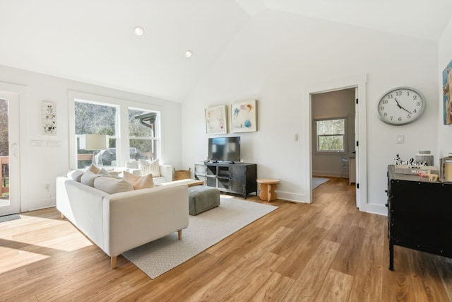 living room with high vaulted ceiling and light wood-type flooring