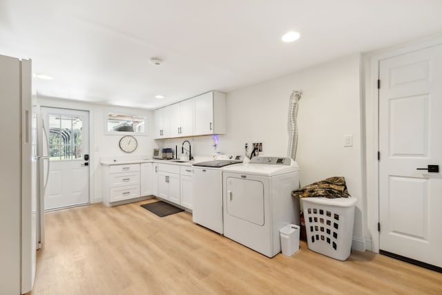 washroom with cabinets, light wood-type flooring, sink, and separate washer and dryer