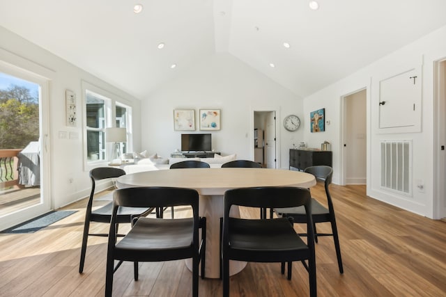 dining area featuring light wood-type flooring and high vaulted ceiling