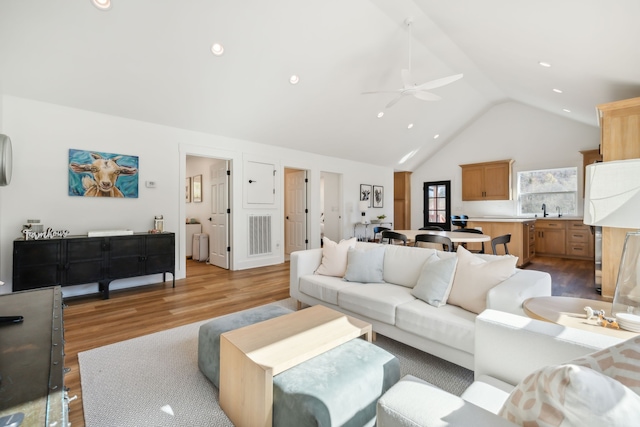 living room featuring ceiling fan, sink, high vaulted ceiling, and wood-type flooring