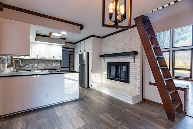 kitchen with white cabinets, dark hardwood / wood-style flooring, kitchen peninsula, and stainless steel refrigerator