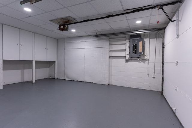 basement featuring a paneled ceiling and electric panel