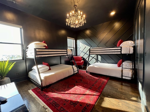 bedroom with wooden walls, dark wood-type flooring, and a notable chandelier