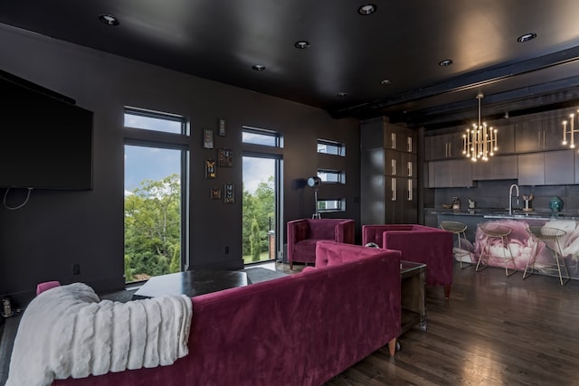 home theater room featuring a notable chandelier, sink, and dark wood-type flooring