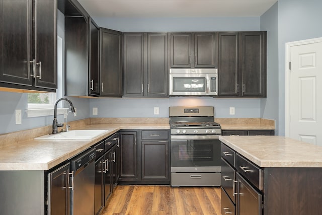 kitchen featuring appliances with stainless steel finishes, dark brown cabinetry, light hardwood / wood-style floors, and sink