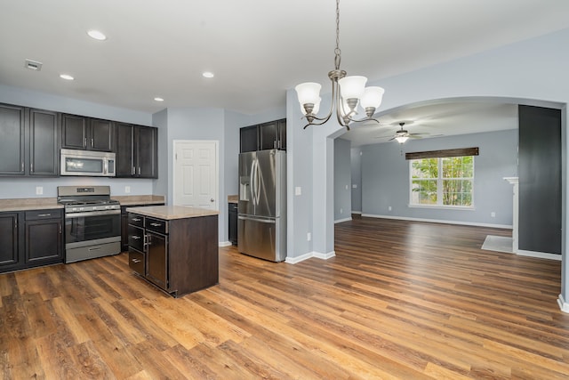 kitchen with hanging light fixtures, ceiling fan, dark brown cabinets, wood-type flooring, and stainless steel appliances