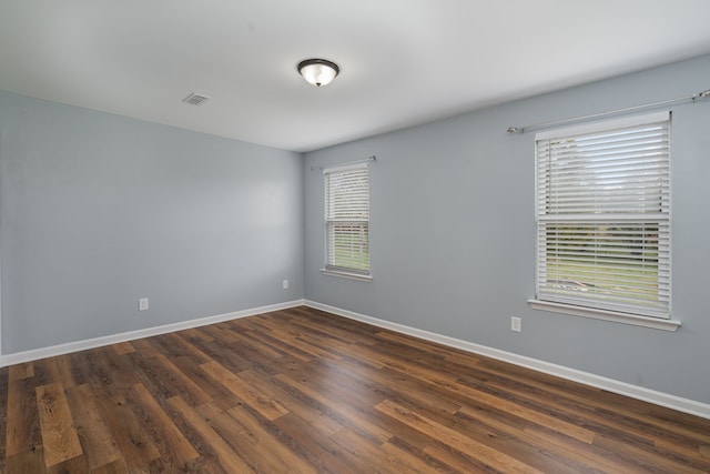 unfurnished room featuring plenty of natural light and dark wood-type flooring