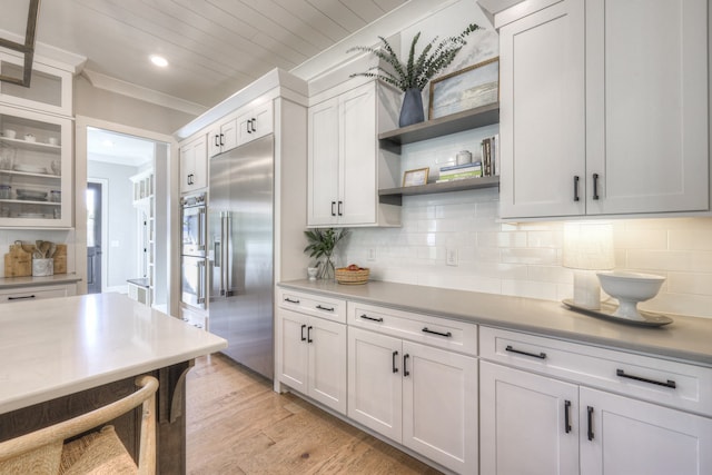 kitchen with white cabinetry, light hardwood / wood-style flooring, stainless steel built in refrigerator, crown molding, and decorative backsplash