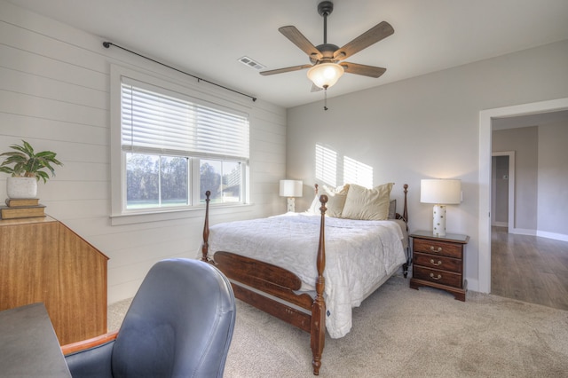 bedroom with hardwood / wood-style floors, ceiling fan, and wooden walls