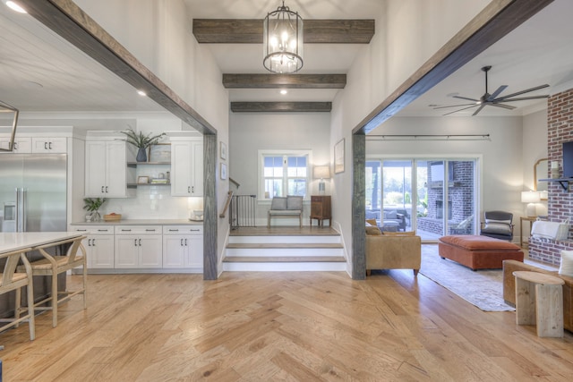 interior space featuring pendant lighting, stainless steel built in fridge, light hardwood / wood-style flooring, beamed ceiling, and white cabinetry