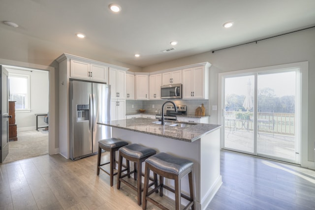 kitchen featuring white cabinets, appliances with stainless steel finishes, dark stone countertops, and sink