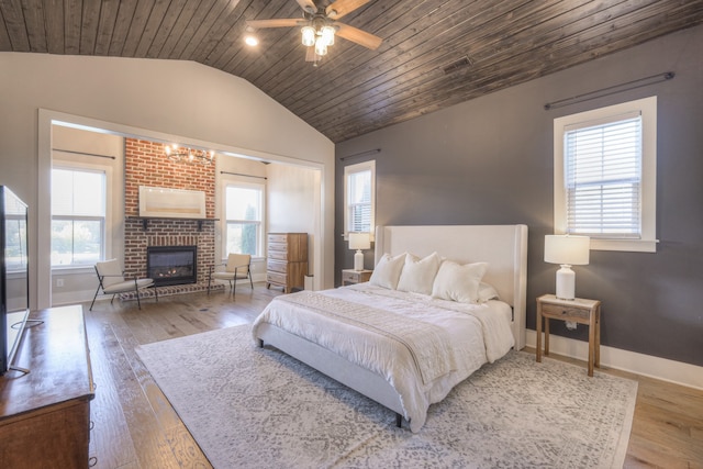 bedroom with hardwood / wood-style floors, lofted ceiling, a brick fireplace, ceiling fan, and wood ceiling