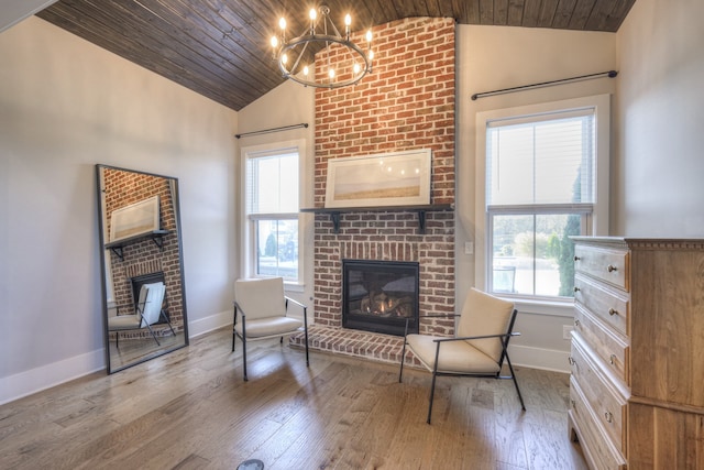 sitting room featuring vaulted ceiling, wood ceiling, and a brick fireplace