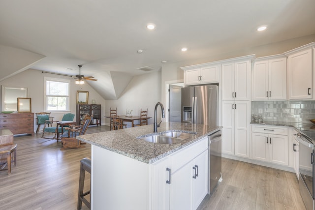 kitchen featuring sink, light wood-type flooring, an island with sink, appliances with stainless steel finishes, and stone countertops