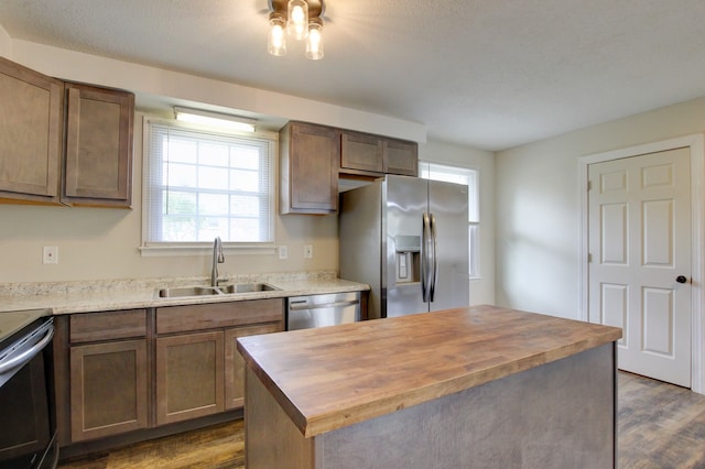 kitchen featuring wood counters, appliances with stainless steel finishes, sink, a center island, and dark hardwood / wood-style floors