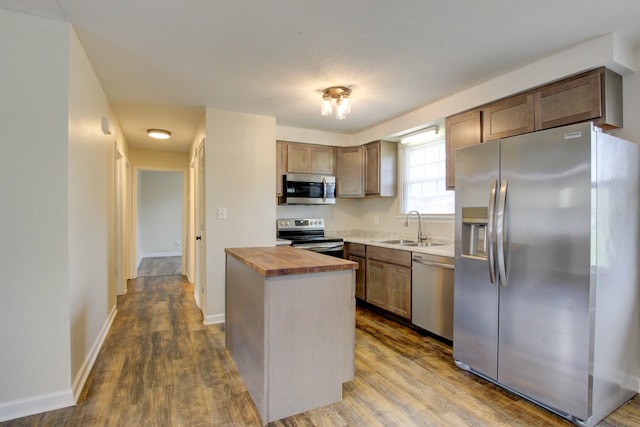 kitchen featuring wood counters, sink, dark hardwood / wood-style floors, appliances with stainless steel finishes, and a kitchen island