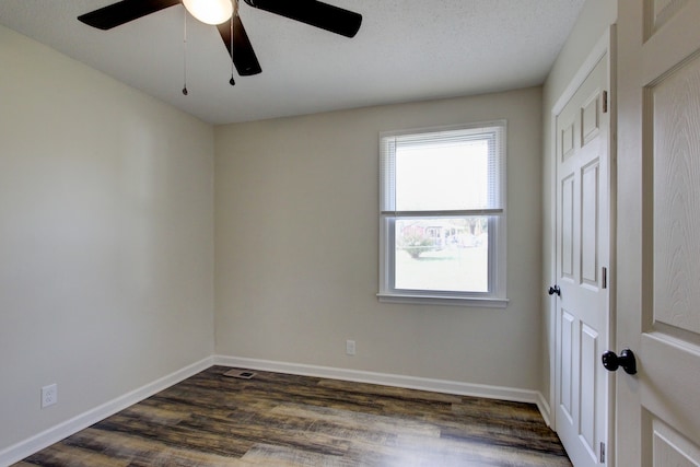 empty room with ceiling fan, dark hardwood / wood-style flooring, and a textured ceiling