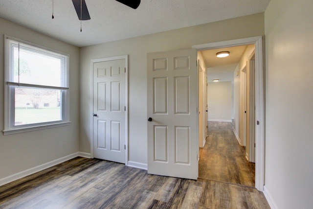 unfurnished bedroom with dark hardwood / wood-style floors, ceiling fan, a textured ceiling, and a closet