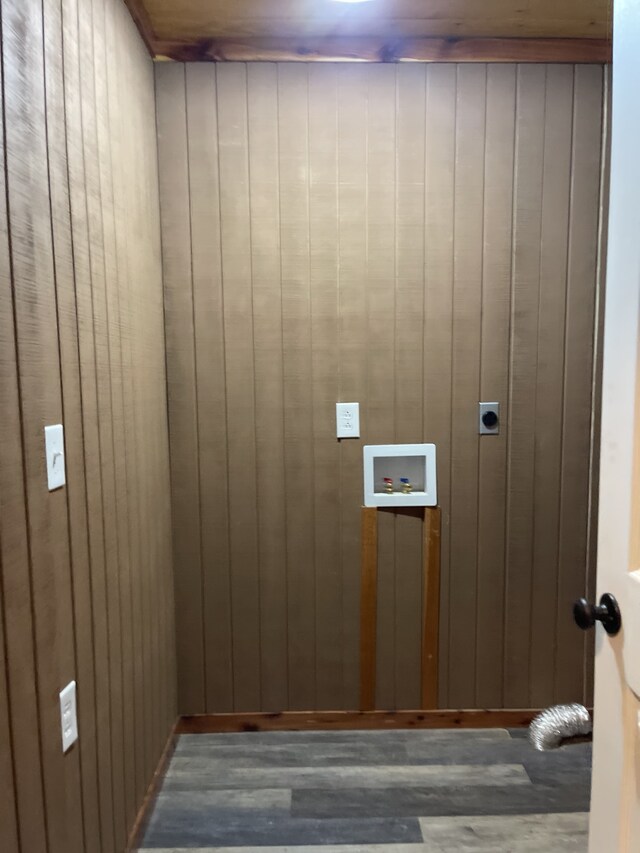 laundry area featuring wooden walls, dark wood-type flooring, and electric dryer hookup