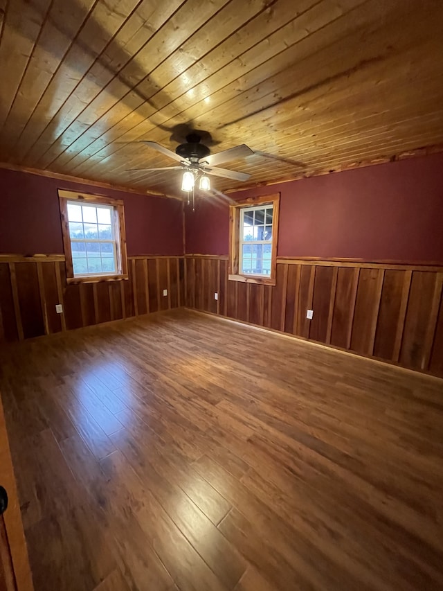 empty room featuring a healthy amount of sunlight, wood-type flooring, and wooden ceiling