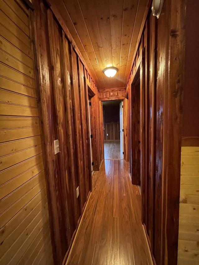 hallway with hardwood / wood-style flooring, wooden ceiling, and wood walls