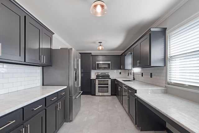 kitchen featuring light stone countertops, appliances with stainless steel finishes, backsplash, ornamental molding, and sink