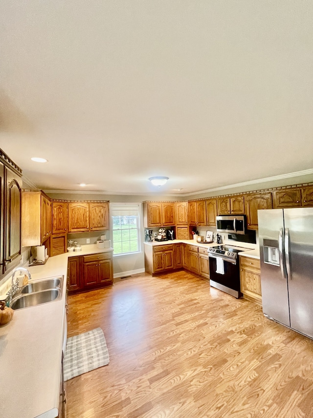 kitchen with ornamental molding, sink, light hardwood / wood-style floors, and appliances with stainless steel finishes