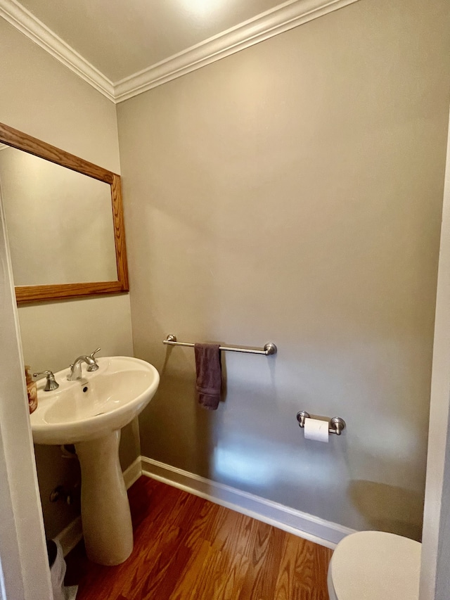 bathroom with toilet, wood-type flooring, and ornamental molding