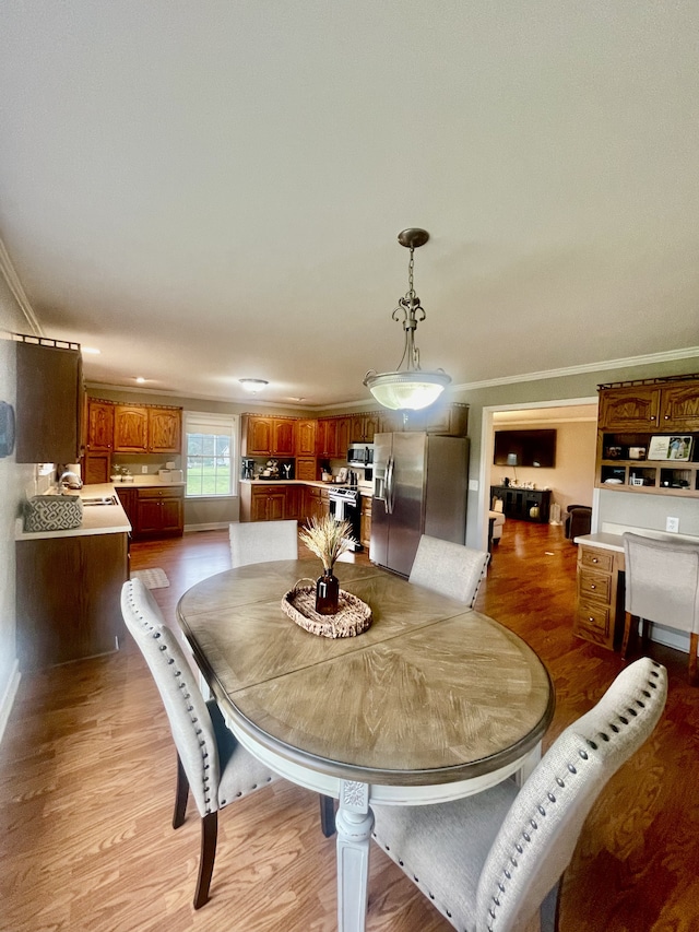 dining space with light wood-type flooring and ornamental molding