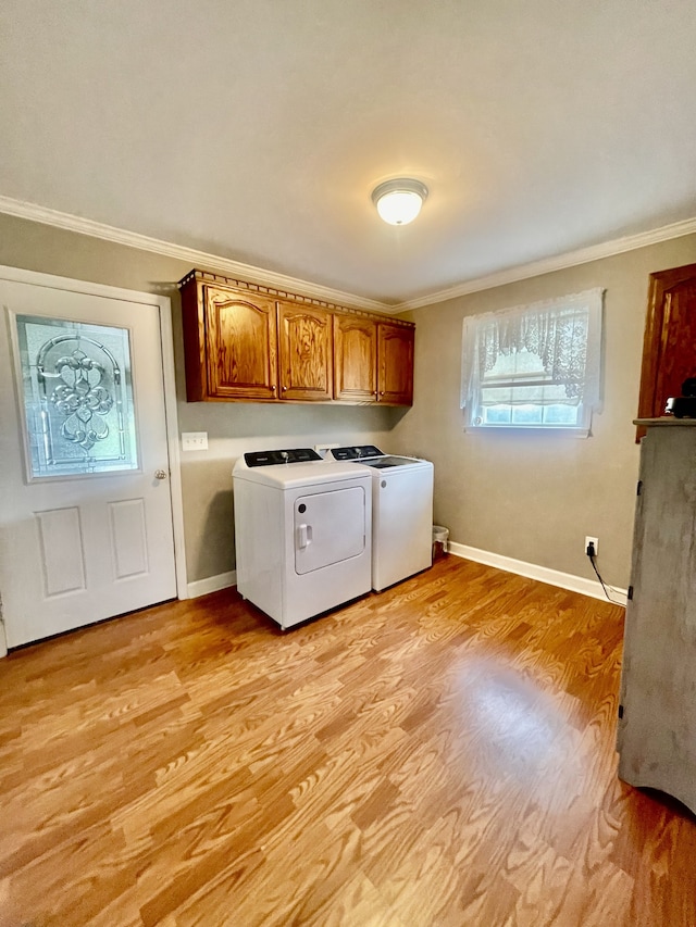 clothes washing area with cabinets, light wood-type flooring, washing machine and dryer, and ornamental molding