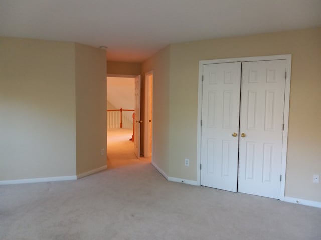 unfurnished bedroom with light colored carpet and a closet