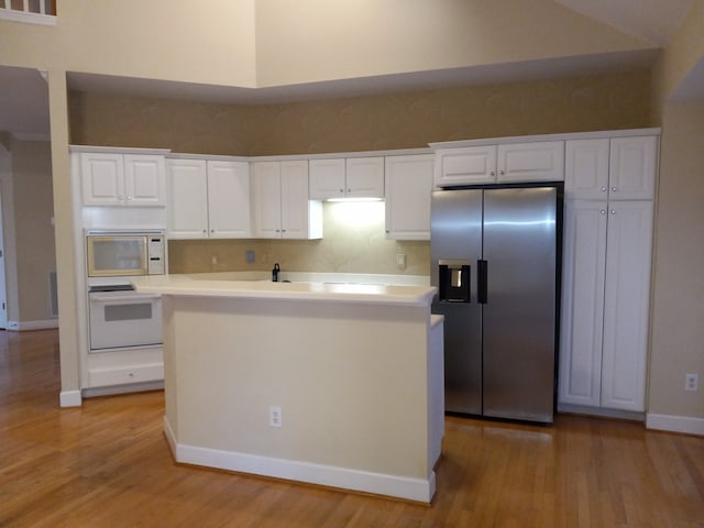 kitchen featuring white cabinetry, a center island, light hardwood / wood-style floors, and white appliances