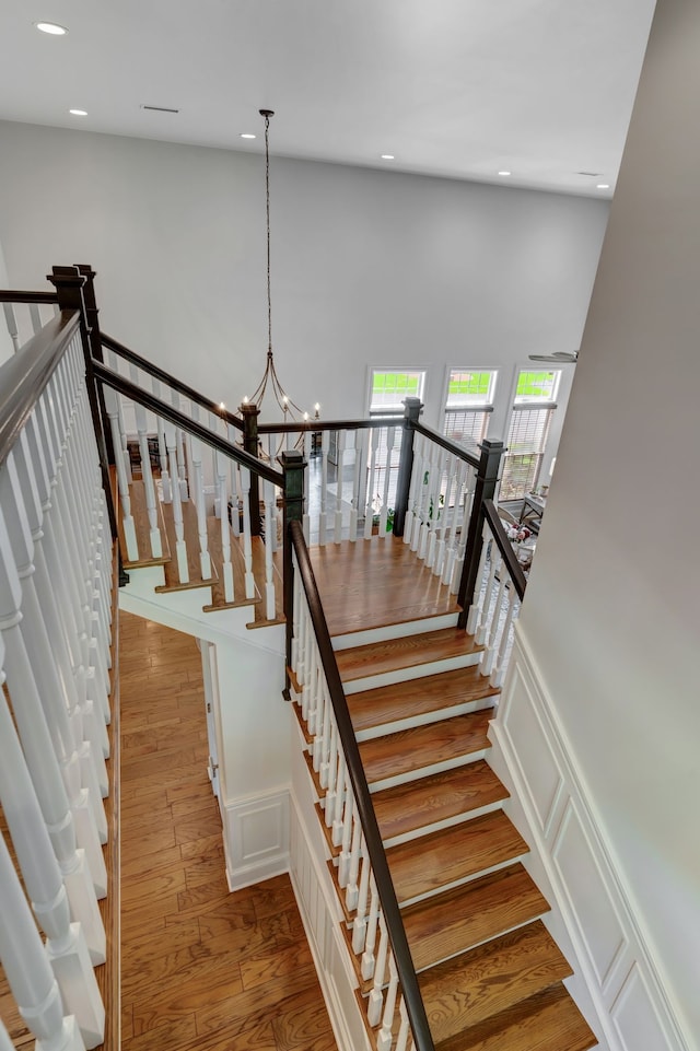 stairs featuring hardwood / wood-style floors, a high ceiling, and a chandelier