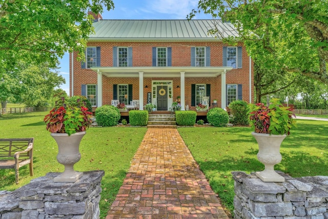 colonial-style house featuring covered porch and a front yard