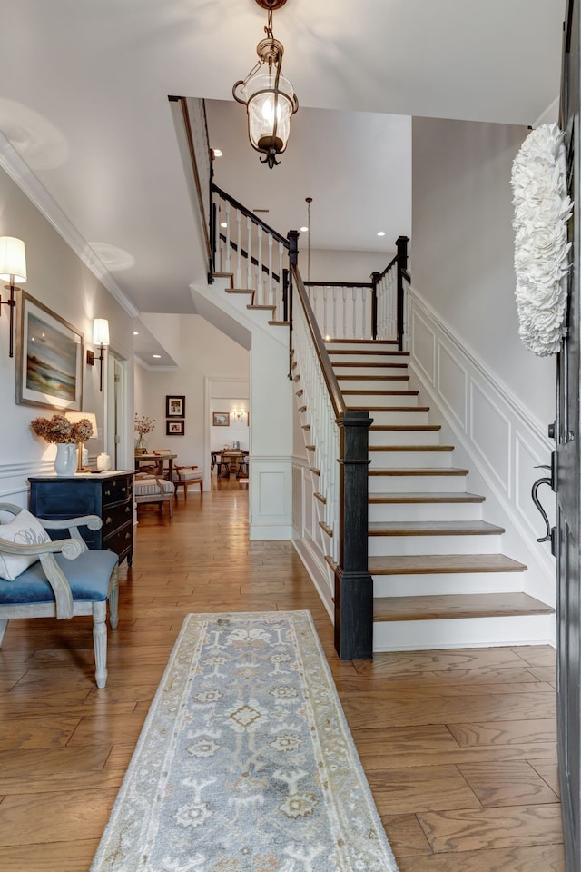 entryway featuring a notable chandelier, wood-type flooring, and crown molding