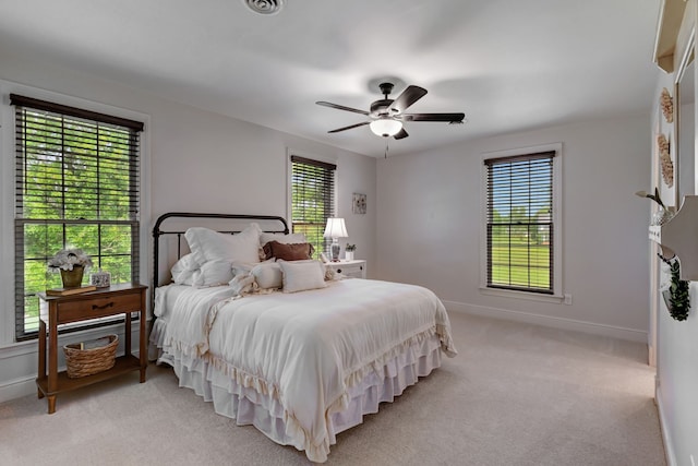 bedroom with light carpet, multiple windows, and ceiling fan