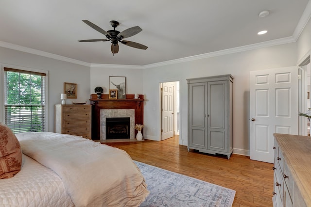 bedroom with a fireplace, light hardwood / wood-style flooring, ceiling fan, and crown molding