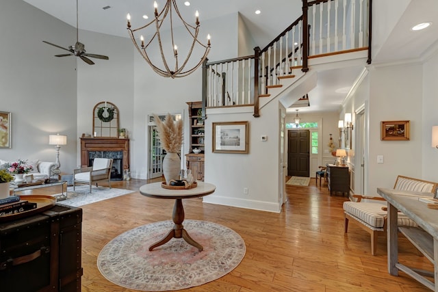 living room with a wealth of natural light, light wood-type flooring, a towering ceiling, and a high end fireplace