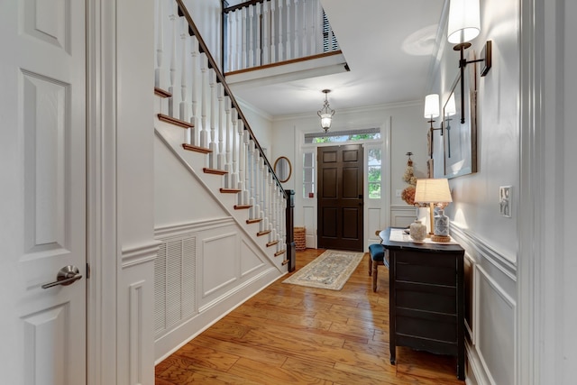 foyer entrance with ornamental molding and light wood-type flooring