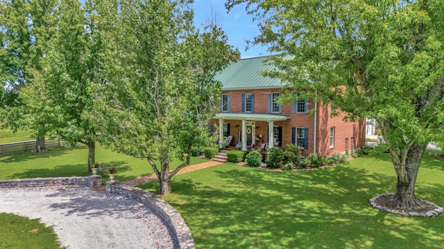 colonial inspired home featuring covered porch and a front yard