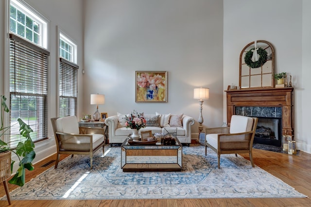 living room featuring hardwood / wood-style flooring, a towering ceiling, and a fireplace