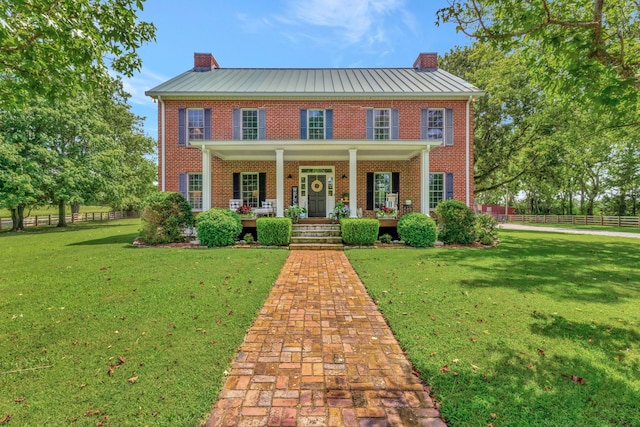 colonial inspired home featuring a porch and a front yard