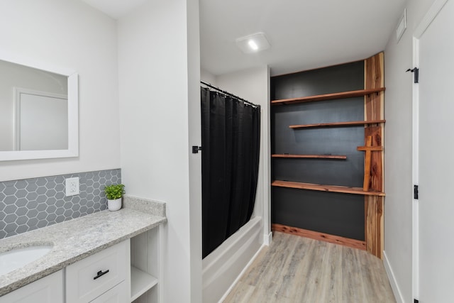 bathroom with hardwood / wood-style floors, vanity, backsplash, and shower / tub combo