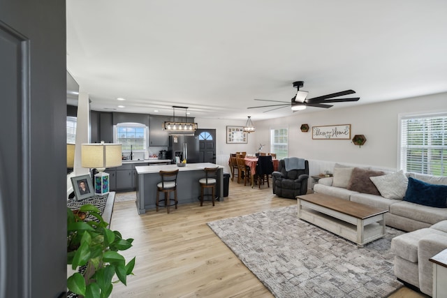 living room with light hardwood / wood-style flooring, ceiling fan, and sink