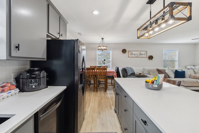 kitchen featuring tasteful backsplash, light hardwood / wood-style flooring, a notable chandelier, pendant lighting, and gray cabinets