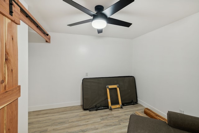 interior space with a barn door, light hardwood / wood-style flooring, and ceiling fan