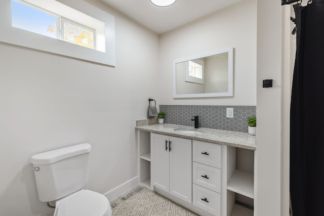 bathroom featuring vanity, toilet, a wealth of natural light, and tasteful backsplash