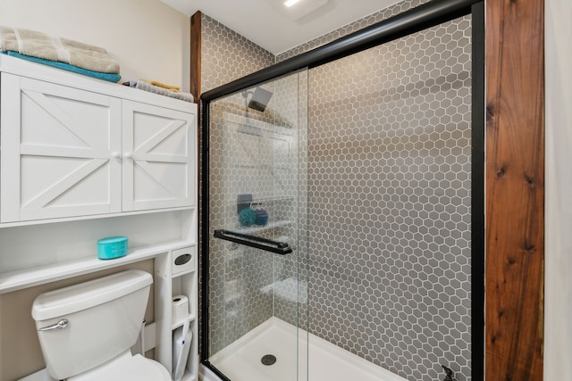 bathroom featuring toilet and a shower with shower door