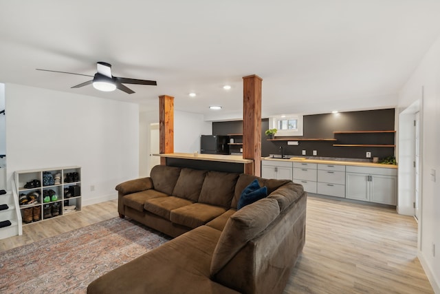 living room with ceiling fan, light wood-type flooring, and sink